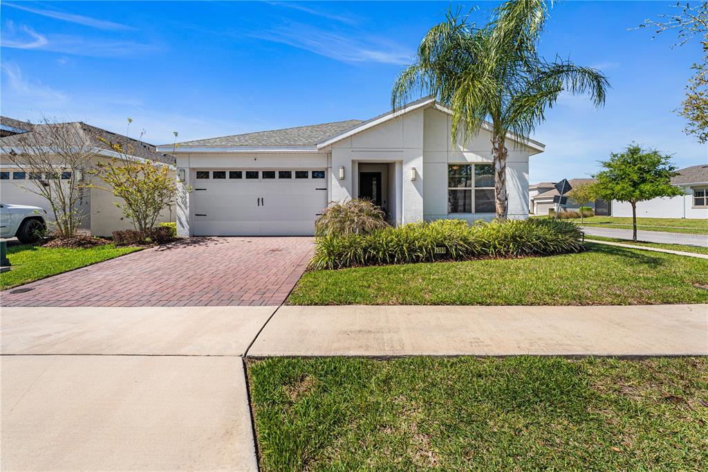 A single-story house with a white exterior, a brick driveway, and a palm tree — 3399 SAGEBRUSH STREET, HARMONY, FL