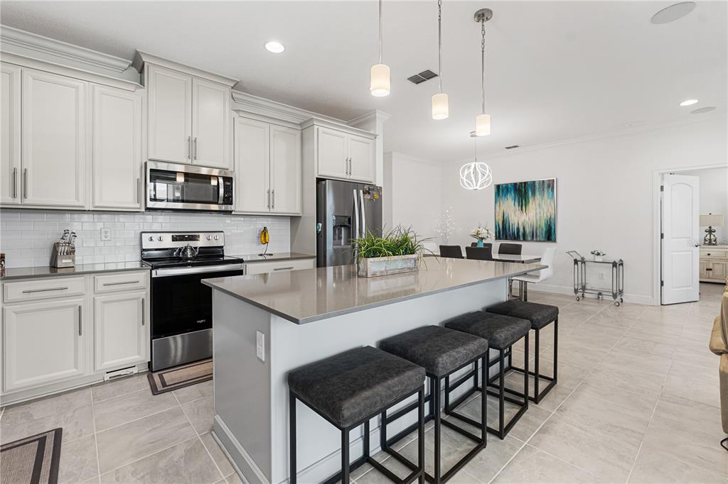 A kitchen with white cabinets, a gray island, stainless steel appliances, and tile flooring — 3399 SAGEBRUSH STREET, HARMONY, FL