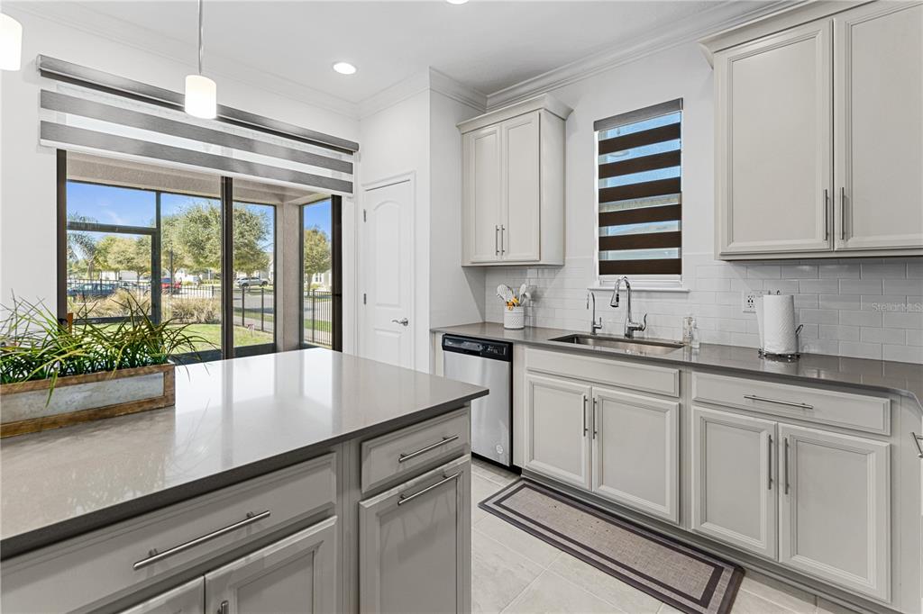 A kitchen features light gray cabinets, quartz countertops, stainless steel appliances, and a sliding glass door — 3399 SAGEBRUSH STREET, HARMONY, FL