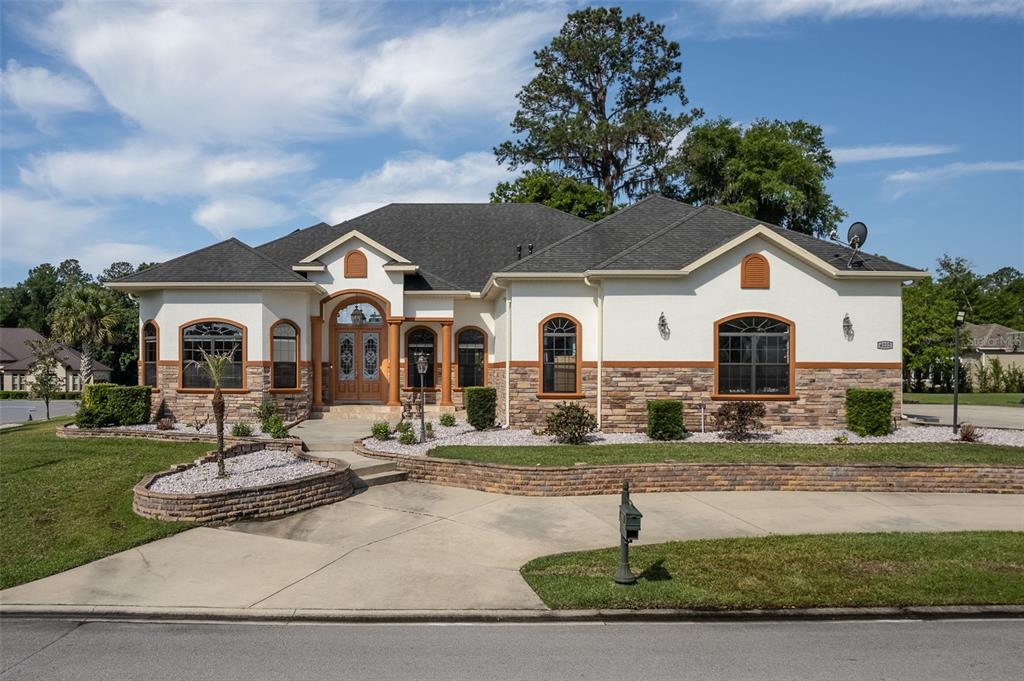 A single-story house with a stucco and stone facade, arched windows, and a paved driveway — 4222 SE 9TH AVENUE, OCALA, FL