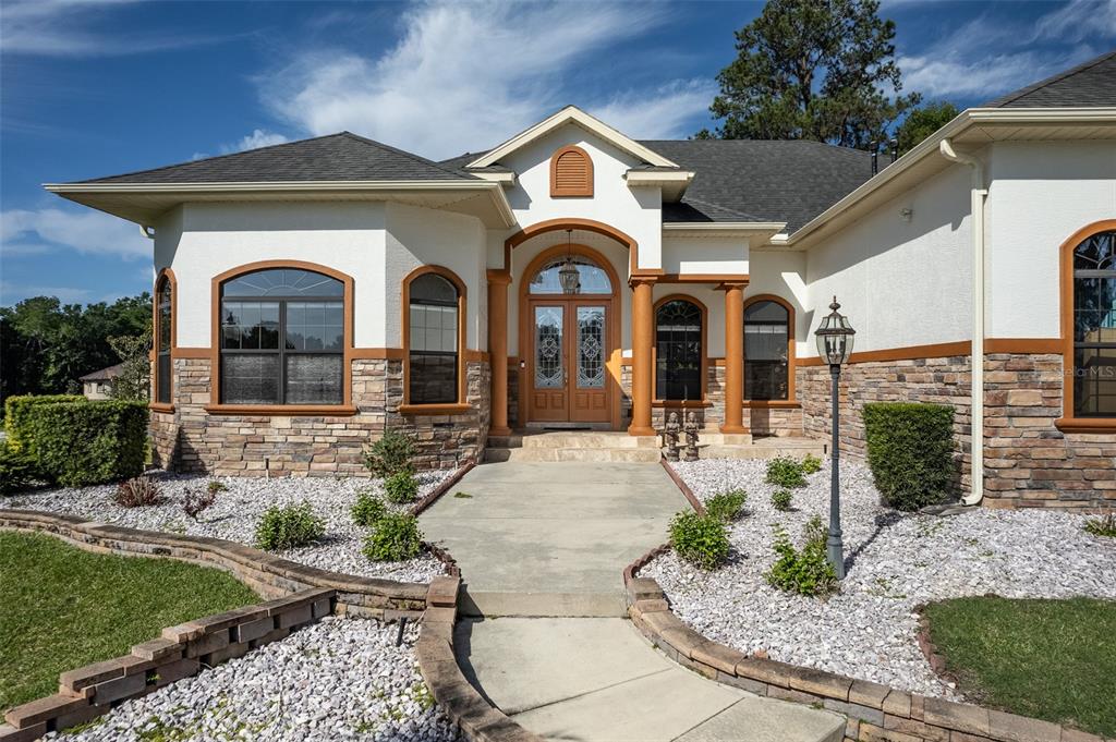 The exterior of a single-story house features stucco walls, stone veneer, and a paved walkway — 4222 SE 9TH AVENUE, OCALA, FL