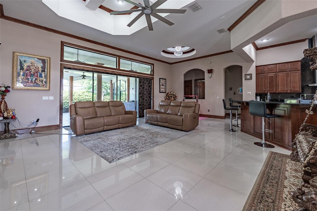 A living room with tile floors, two brown sofas, and an open kitchen area — 4222 SE 9TH AVENUE, OCALA, FL