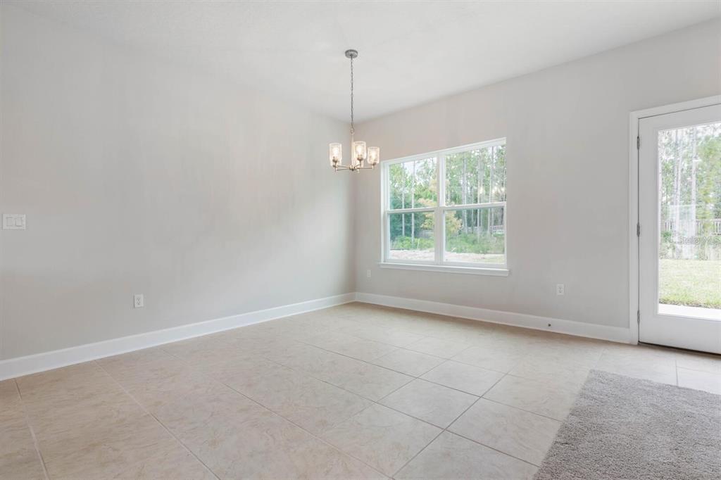 An empty dining area features tile flooring, a chandelier, a large window, and a glass door — 9 SQUIRREL PLACE, PALM COAST, FL