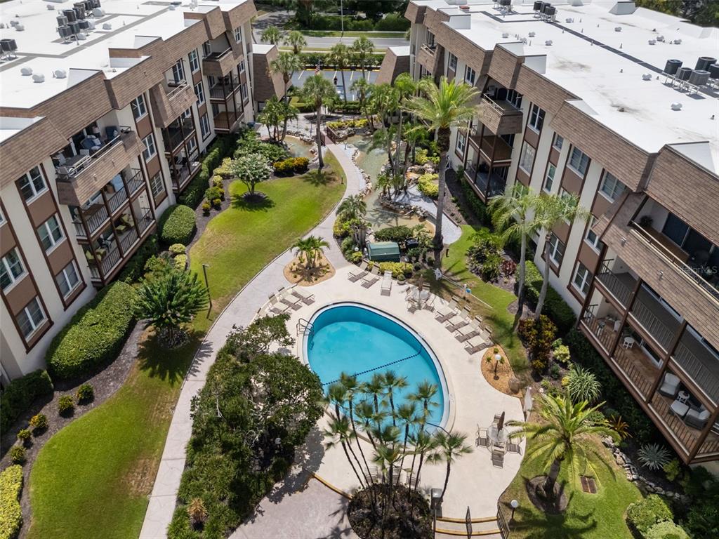 A multi-story apartment building features balconies overlooking a landscaped lawn and a paved walkway — 3021 COUNTRYSIDE BOULEVARD UNIT 21A, CLEARWATER, FL