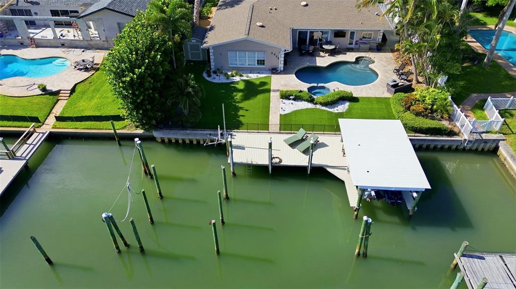 An aerial view of a waterfront home featuring a private dock, boat lift, and pool — 137 12TH STREET E, TIERRA VERDE, FL