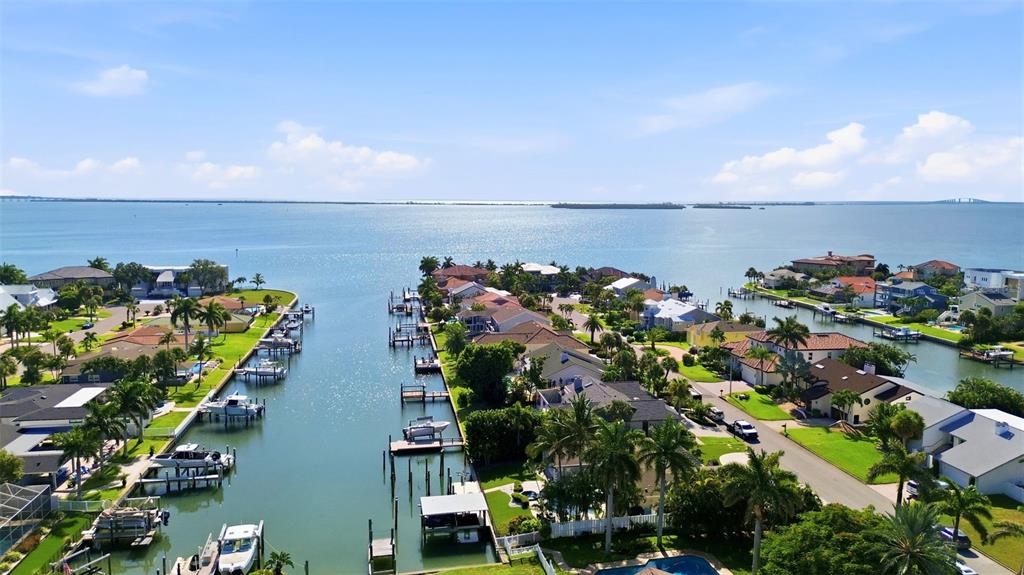 An aerial view shows waterfront homes with private docks along a canal leading to a bay — 137 12TH STREET E, TIERRA VERDE, FL