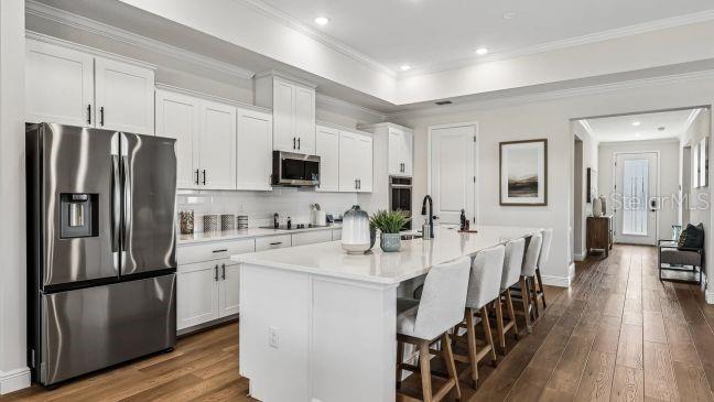 A modern kitchen features white cabinets, stainless steel appliances, a large island, and hardwood floors — 5017 N PEPPERMINT DRIVE, BEVERLY HILLS, FL