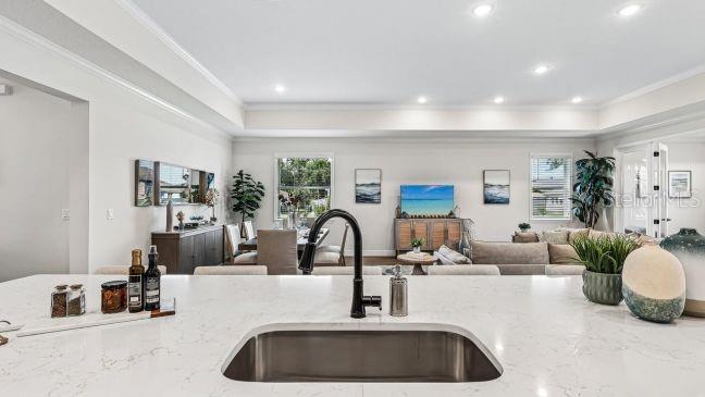 A kitchen island with a sink overlooks an open-concept living and dining area — 5017 N PEPPERMINT DRIVE, BEVERLY HILLS, FL