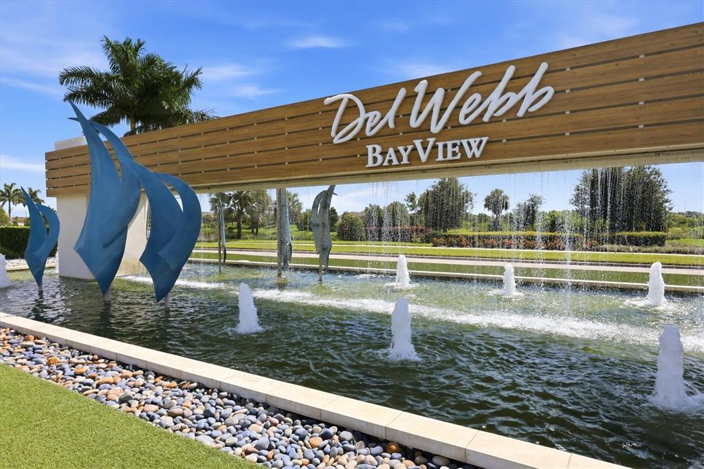 A wooden entrance sign for Del Webb BayView stands above a fountain with blue sculptures — 10708 SARATOGA PLACE, PARRISH, FL
