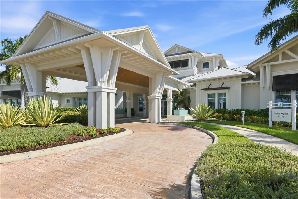 The exterior of a clubhouse building features a large covered entryway and landscaped grounds — 10708 SARATOGA PLACE, PARRISH, FL