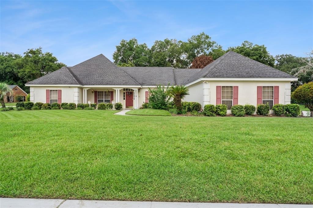 A single-story house with a gray shingled roof, beige stucco walls, and red shutters — 2512 TRYON PLACE, WINDERMERE, FL