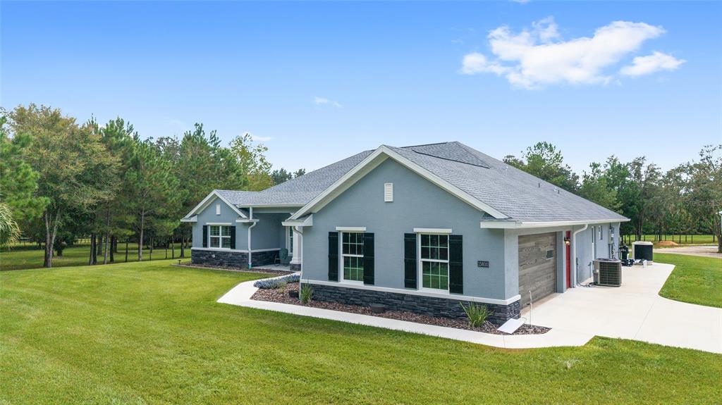 A single-story gray house with a stone base, black shutters, and an attached garage — 15600 NW 185TH STREET, WILLISTON, FL