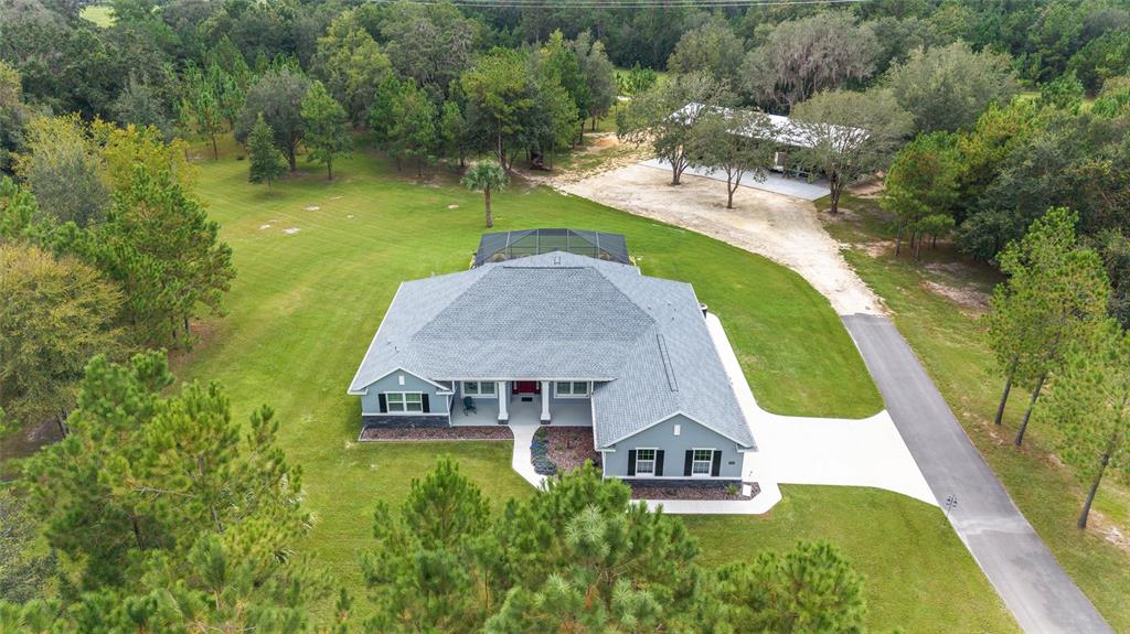 An aerial view shows a gray house with a screened patio and a detached garage — 15600 NW 185TH STREET, WILLISTON, FL