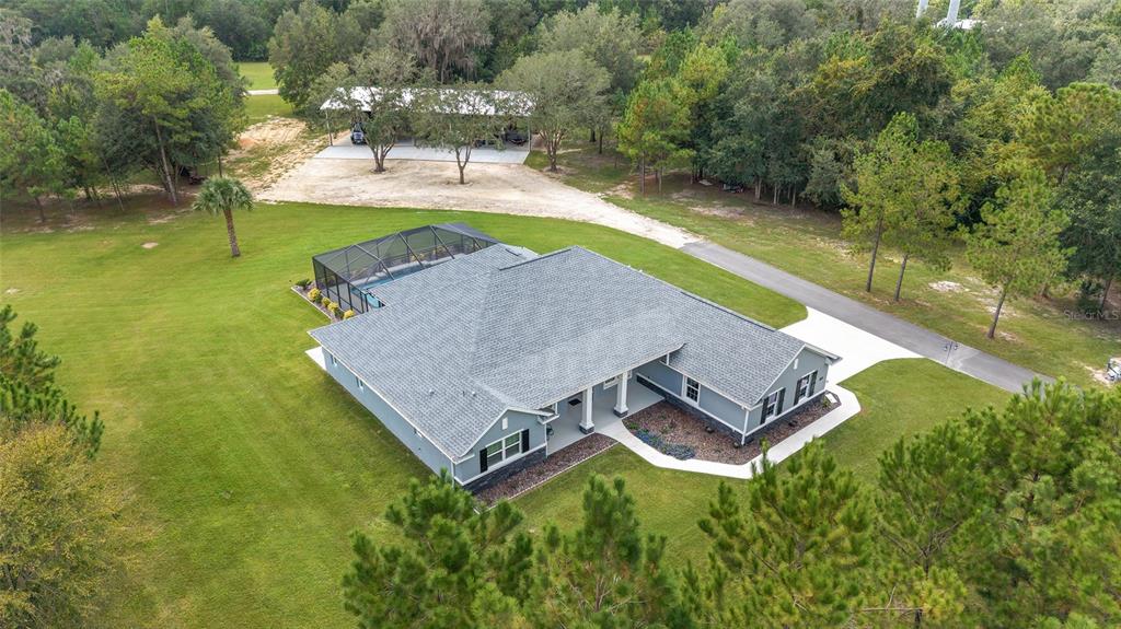 An aerial view shows a single-story house with a pool enclosure and a detached carport — 15600 NW 185TH STREET, WILLISTON, FL