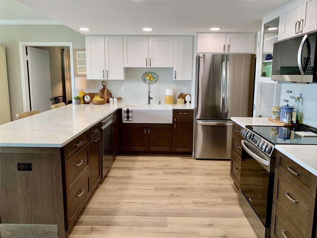 A kitchen with white upper cabinets, dark wood lower cabinets, and a white farmhouse sink — 1655 S HIGHLAND AVENUE UNIT I379, CLEARWATER, FL