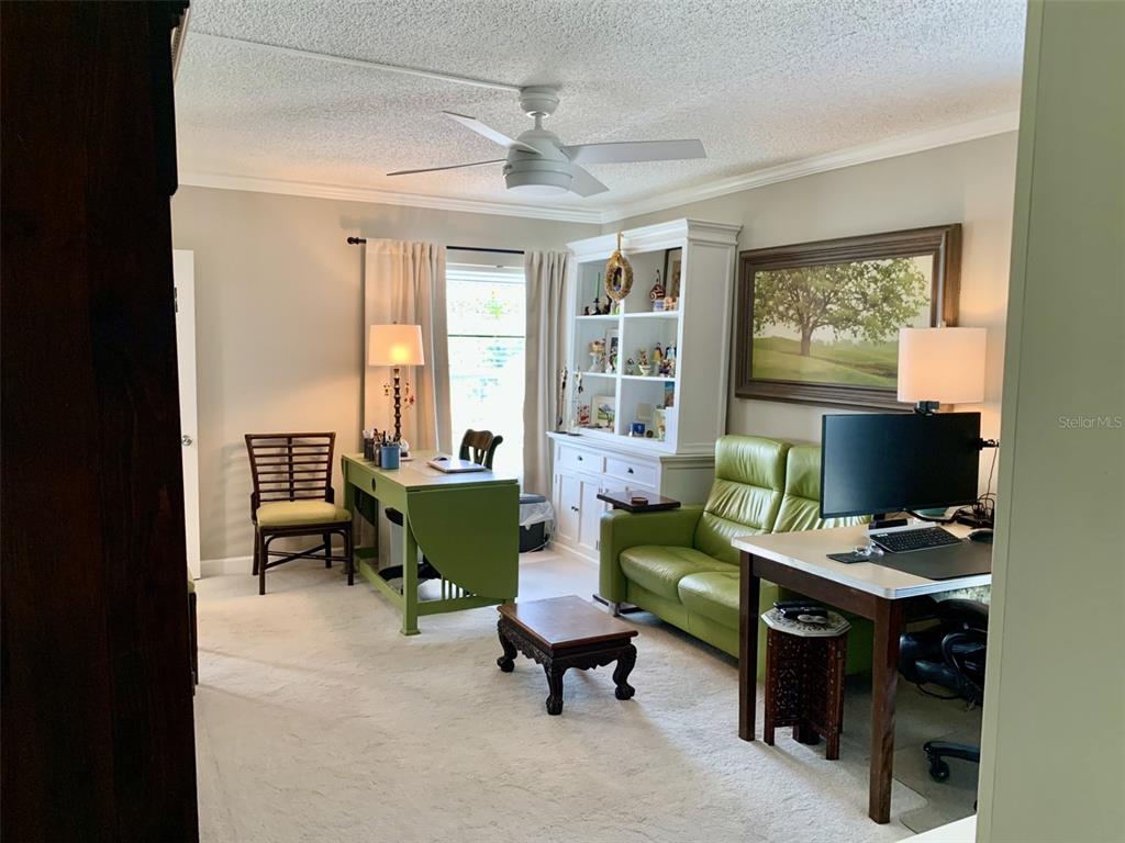 A home office features a green desk, a green sofa, a bookshelf, and a ceiling fan — 1655 S HIGHLAND AVENUE UNIT I379, CLEARWATER, FL