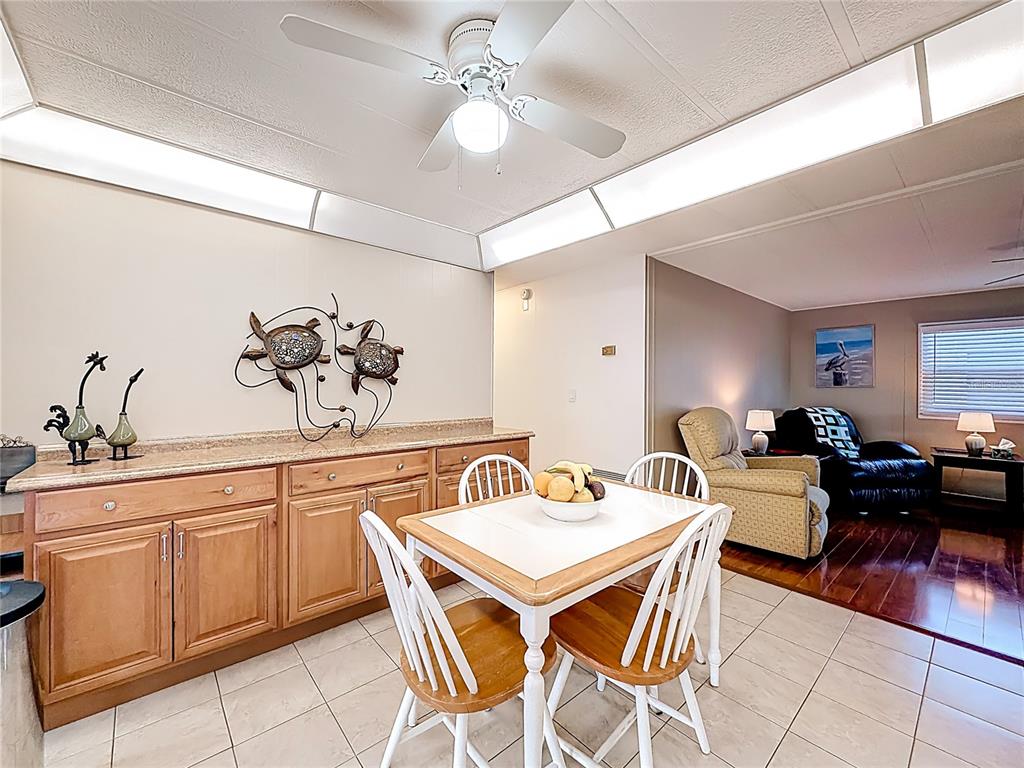 A dining area features light wood cabinets, a white table with chairs, and tile flooring — 10184 106TH AVENUE UNIT 26, LARGO, FL