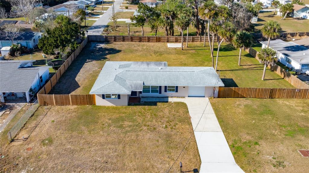 An aerial view shows a single-story house with a gray roof and a concrete driveway — 123 W OCEAN AVENUE, EDGEWATER, FL