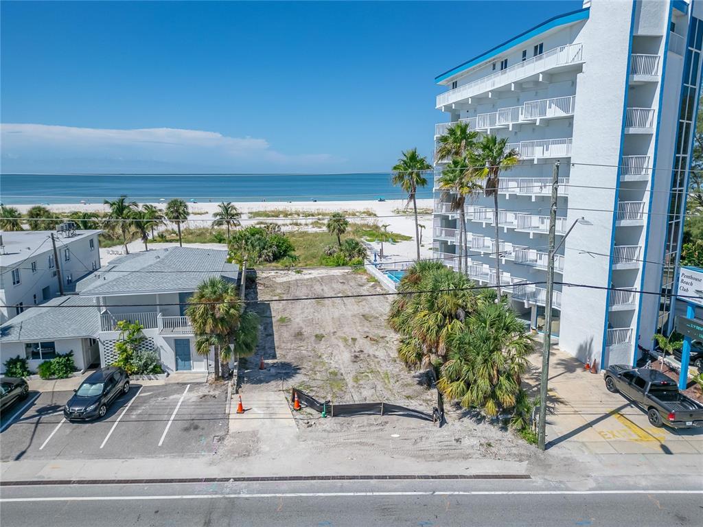 An aerial view shows a vacant rectangular lot situated between two buildings near the beach — 10178 GULF BOULEVARD, TREASURE ISLAND, FL