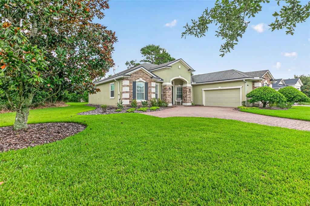 A single-story house with a stone facade, green stucco walls, and a paved driveway — 533 CHRISTINA DRIVE, ST AUGUSTINE, FL
