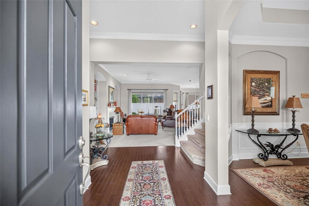 An entryway with hardwood floors leads to a living room with a staircase and furniture — 533 CHRISTINA DRIVE, ST AUGUSTINE, FL