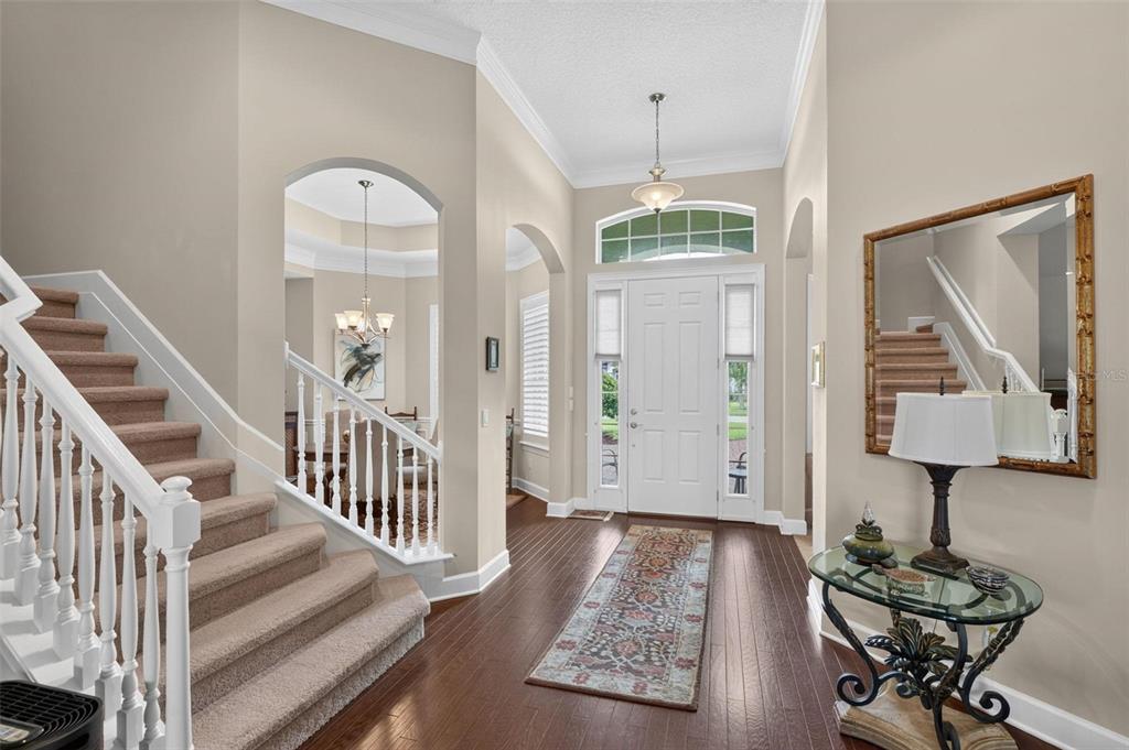 An entryway features a carpeted staircase, hardwood floors, a glass console table, and a front door — 533 CHRISTINA DRIVE, ST AUGUSTINE, FL