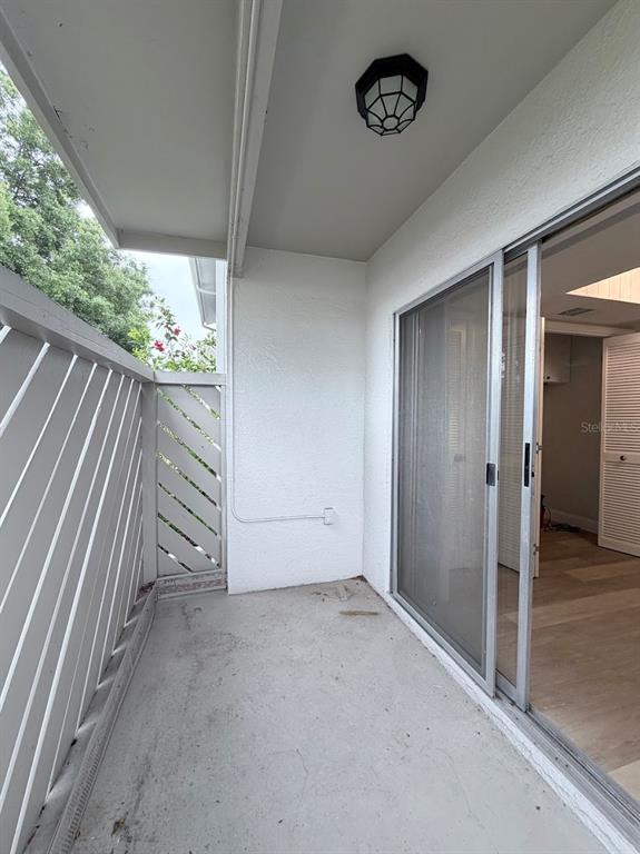 A covered balcony features a concrete floor, white diagonal lattice walls, and a sliding glass door — 12406 EAGLESWOOD DRIVE UNIT B, HUDSON, FL