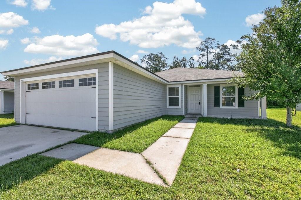 A single-story house with gray siding, a two-car garage, and a concrete walkway — 7082 PLYMOUTH GROVE COURT, JACKSONVILLE, FL