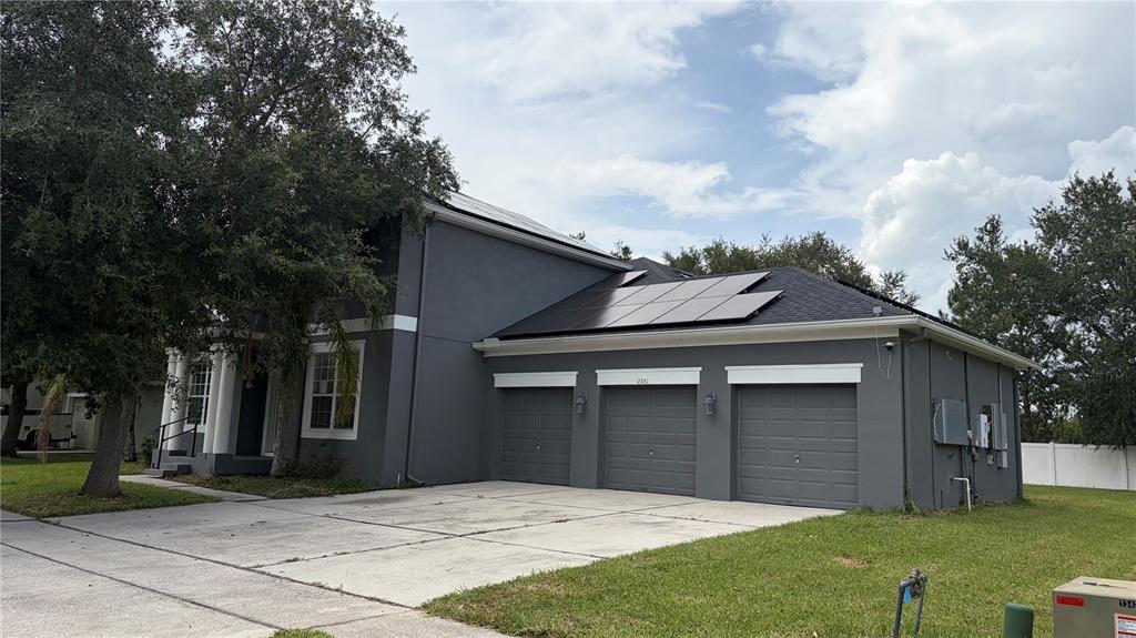 A two-story gray house with a three-car garage and a large tree in front — 2981 MARSHFIELD PRESERVE WAY, KISSIMMEE, FL