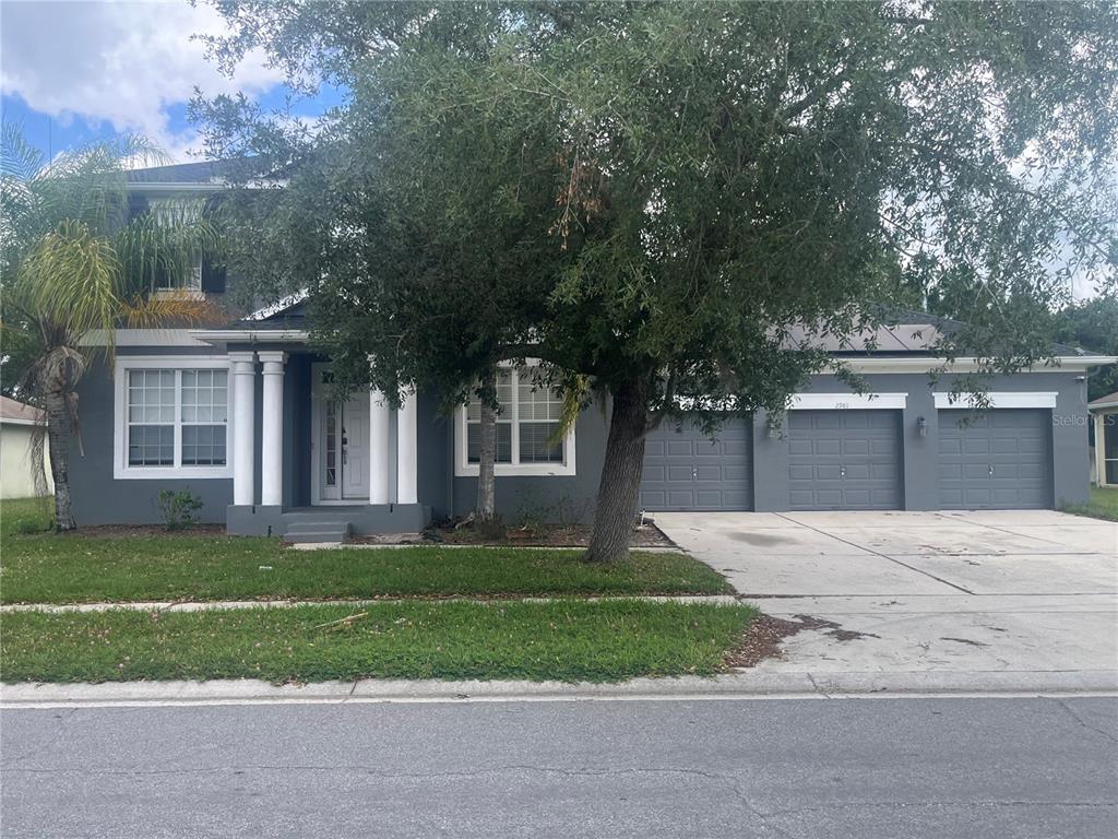 A two-story gray house with white trim, columns, and a palm tree in the front yard — 2981 MARSHFIELD PRESERVE WAY, KISSIMMEE, FL