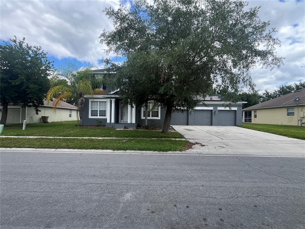 A three-car garage with solar panels on the roof under a blue sky — 2981 MARSHFIELD PRESERVE WAY, KISSIMMEE, FL