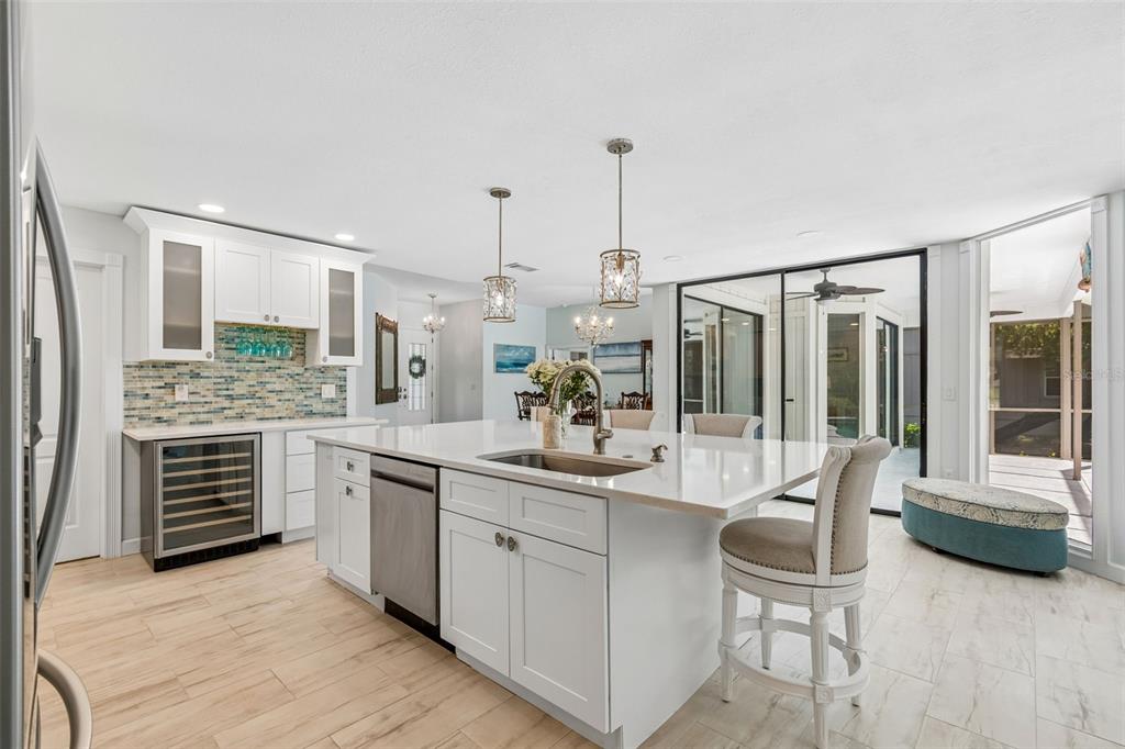 A bright kitchen features a white island with a sink, stainless appliances, and tile flooring — 4627 TRAILS DRIVE, SARASOTA, FL
