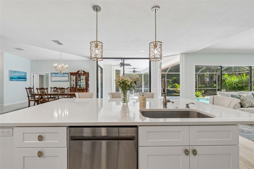 A kitchen island with a stainless steel sink and dishwasher faces a bright living area — 4627 TRAILS DRIVE, SARASOTA, FL