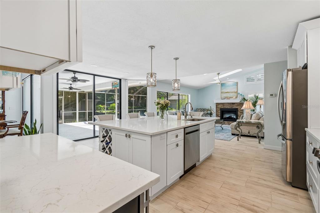 A modern kitchen with a white island and stainless steel appliances overlooks a living area — 4627 TRAILS DRIVE, SARASOTA, FL
