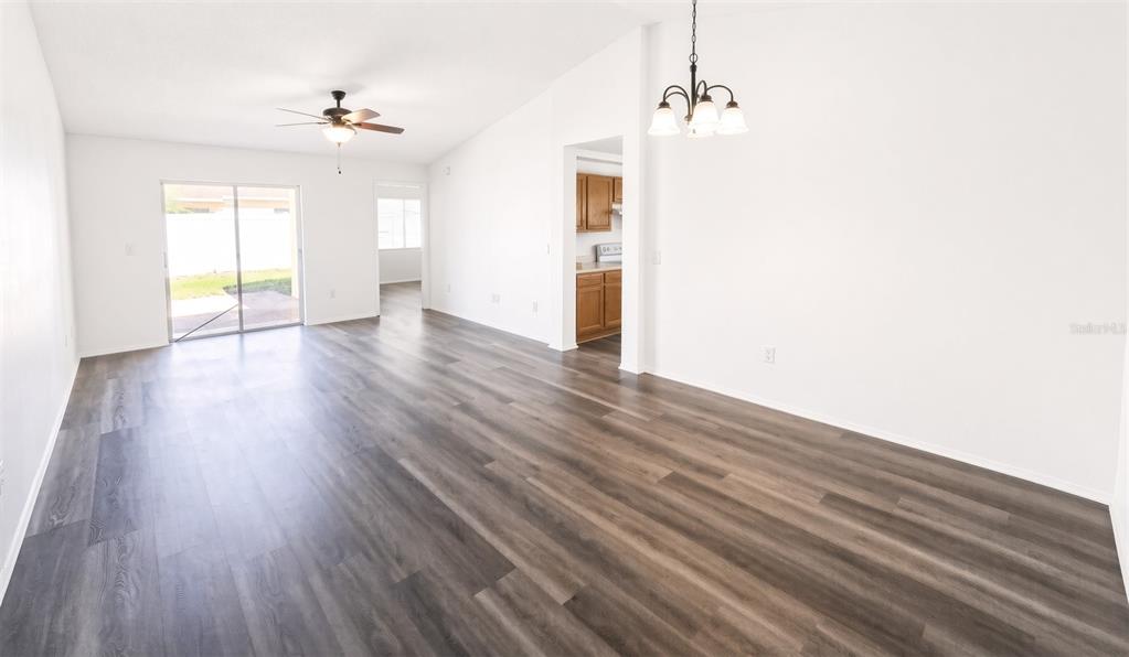 An open-concept living and dining area features white walls, wood-look flooring, and a sliding glass door — 1410 OAKFORD COURT, BRANDON, FL