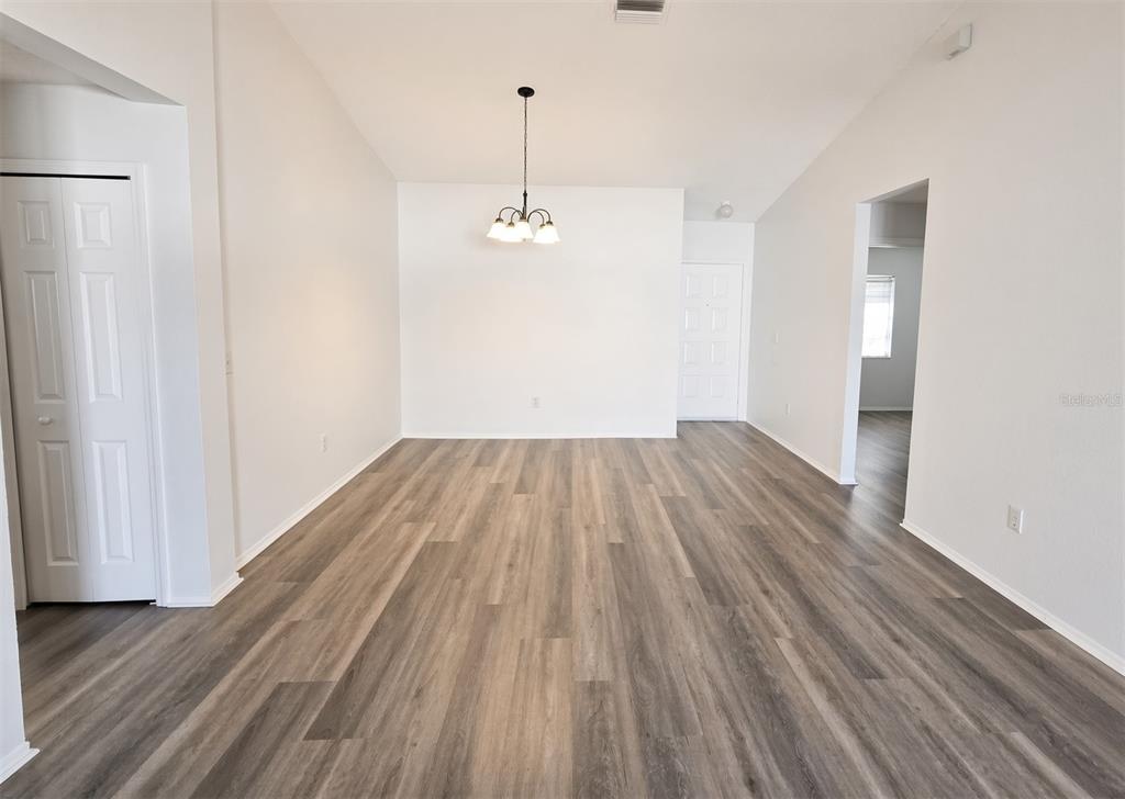 An empty room features light-colored walls, a chandelier, and wood-look vinyl plank flooring — 1410 OAKFORD COURT, BRANDON, FL