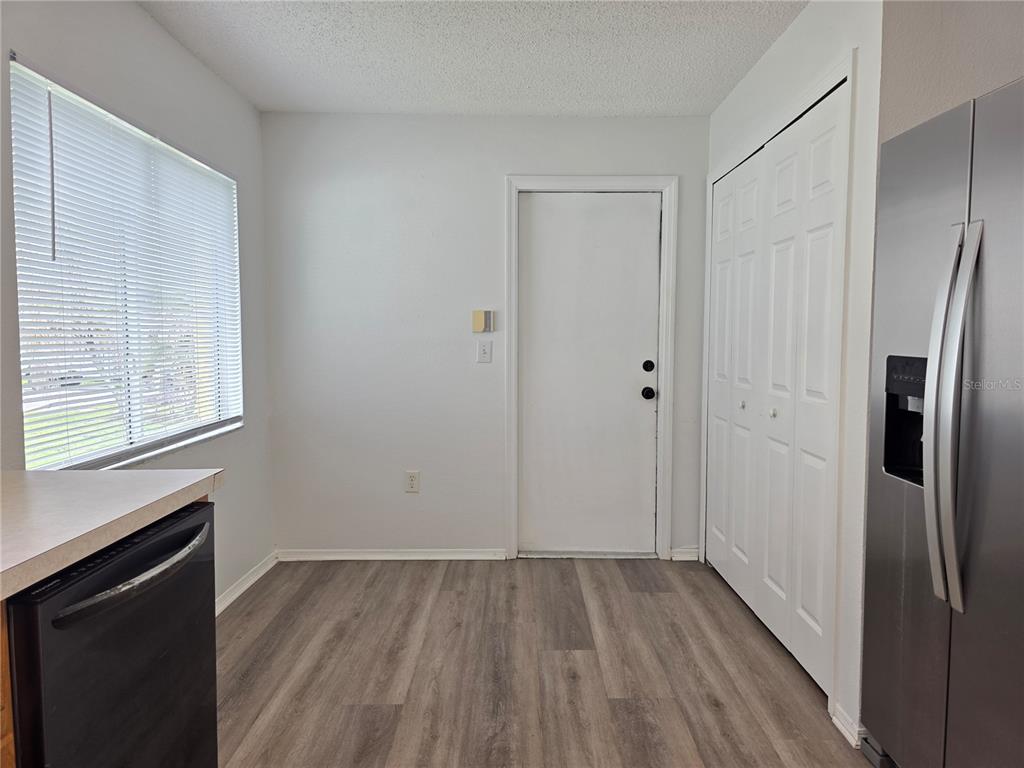 A kitchen area features wood-look flooring, a window with blinds, a white door, and a closet — 1410 OAKFORD COURT, BRANDON, FL