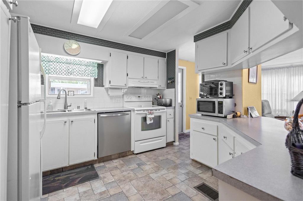 A kitchen features white cabinets, stainless steel appliances, a tiled floor, and a breakfast bar — 2100 KINGS HIGHWAY UNIT 27, PORT CHARLOTTE, FL