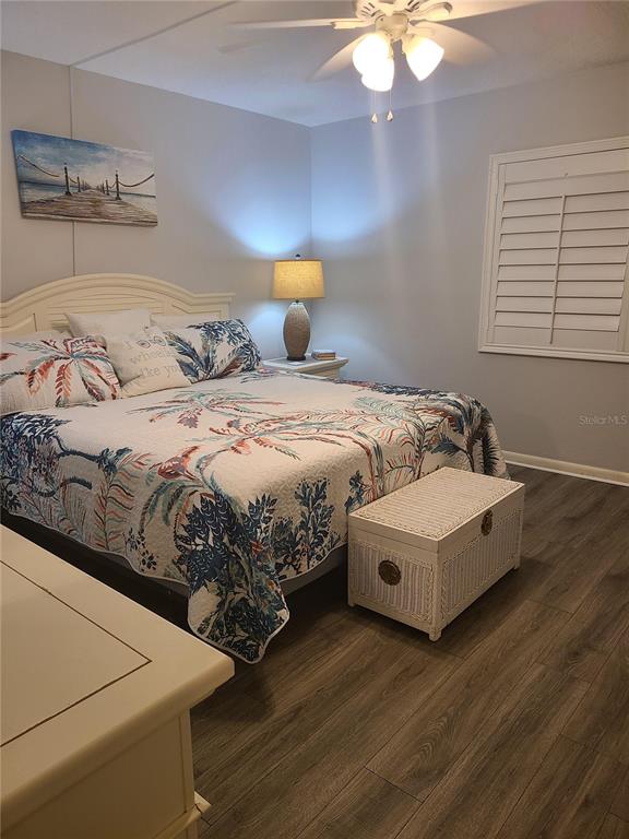 A bedroom features a bed with a patterned quilt, a white chest, and wood-look flooring — 815 OCEAN SHORE BOULEVARD UNIT 12B, ORMOND BEACH, FL