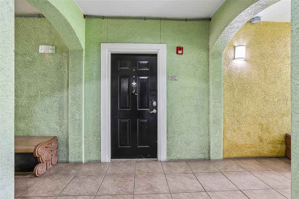 A black front door with a knocker is centered on a lime green stucco wall — 1810 E PALM AVENUE UNIT 5322, TAMPA, FL