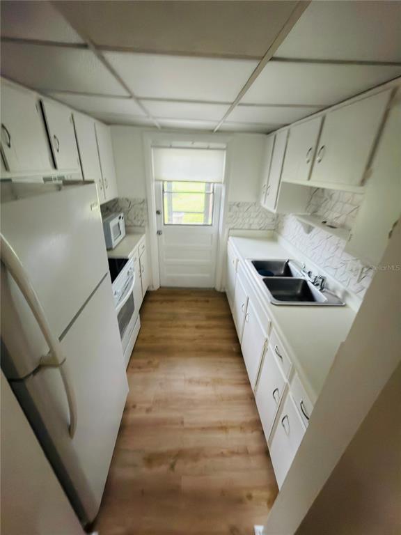 A white kitchen features white cabinets, a glass-top stove, and a white microwave — 5467 HANSEL AVENUE UNIT H15, ORLANDO, FL