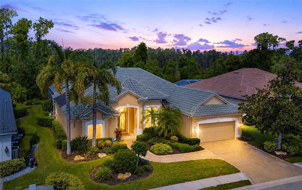 An aerial view of a tan single-story house with a green tile roof at dusk — 4834 88TH STREET E, BRADENTON, FL