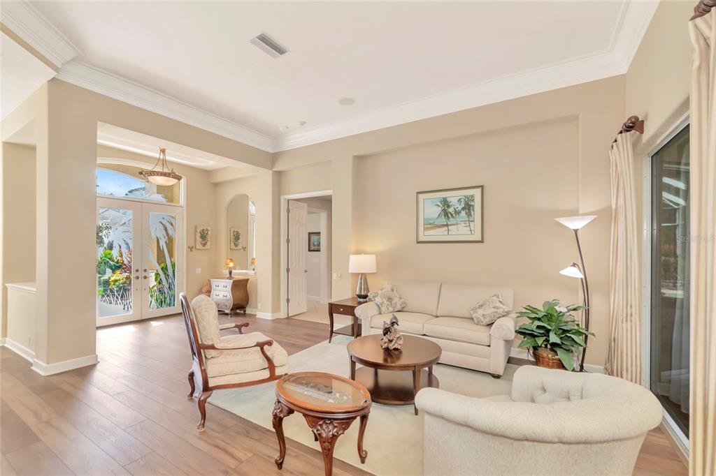 A living room with light-colored furniture, a round coffee table, and wood-look flooring — 4834 88TH STREET E, BRADENTON, FL