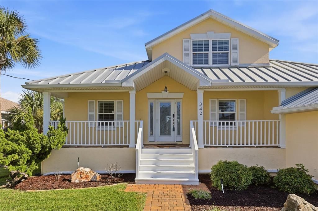 A yellow house with a metal roof, white porch railings, and a front staircase — 342 N 12TH STREET, FLAGLER BEACH, FL