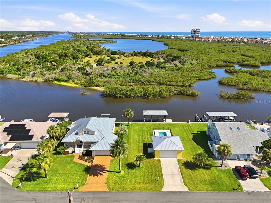 An aerial view shows two waterfront houses with docks, pools, and lawns along a bay — 342 N 12TH STREET, FLAGLER BEACH, FL