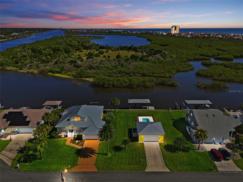 An aerial view shows a waterfront house with a detached garage and a backyard dock — 342 N 12TH STREET, FLAGLER BEACH, FL
