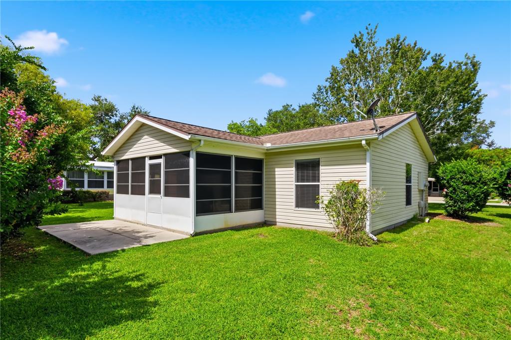A single-story house with light siding, a screened-in porch, and a concrete patio — 25110 BELLEVUE, LEESBURG, FL