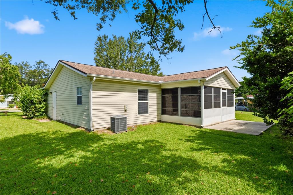 A light-colored vinyl-sided house features a screened-in porch and a concrete patio in the backyard — 25110 BELLEVUE, LEESBURG, FL