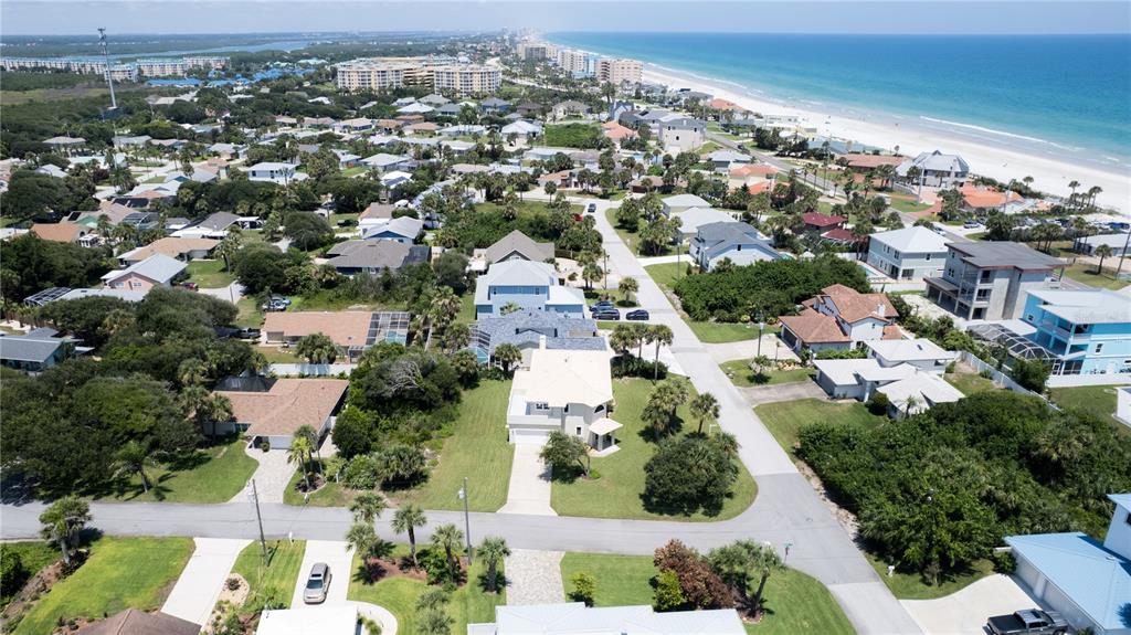 An aerial view shows a coastal neighborhood with houses, lush vegetation, and a sandy beach — 50 ALBERTA AVENUE, PONCE INLET, FL
