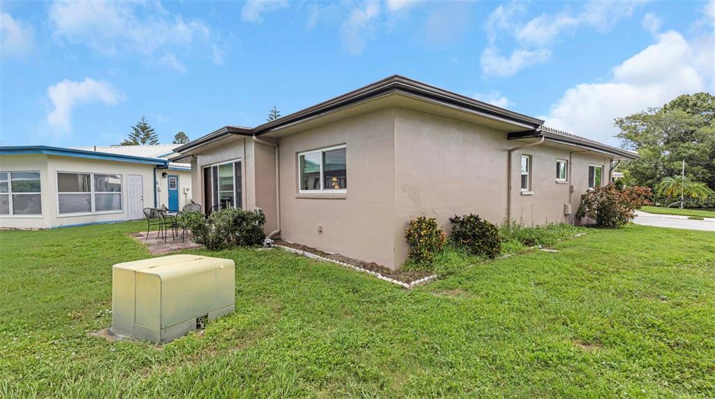 The exterior of a beige, single-story house features a small patio and a utility box — 5355 FERNDALE PLACE N, PINELLAS PARK, FL